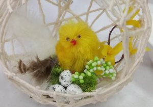 Ozdoba wielkanocna czyli jajko ażurowe z żółtym kurczakiem w środku oraz małymi jajeczkami przygotowana przez seniorów z Klubu Senior+.