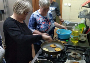 Seniorzy będący uczestnikami Klubu "Senior+" w Brenicy pieką placki ziemniaczane w ramach zajęć kulinarnych.