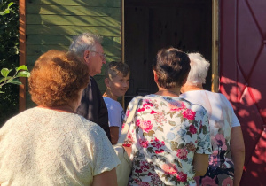 Seniorzy stoją przy wejściu do api-domku.